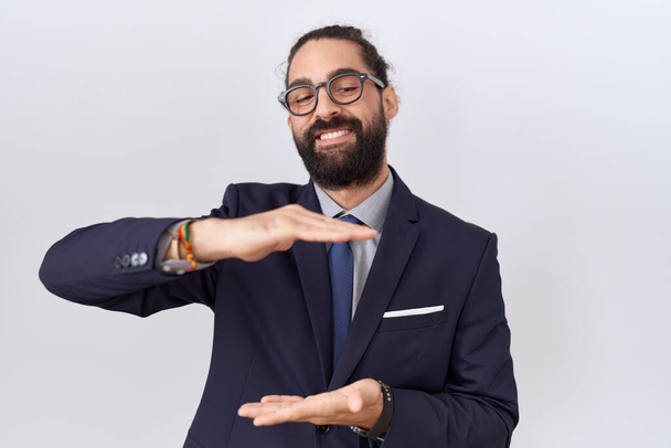 Spanyol férfi szakállas öltönyben és nyakkendős gesztussal, kezén nagy és nagy méretű jel, intézkedés szimbólum. mosolyogva néz a kamerába. mérési koncepció.  - Fotó, kép