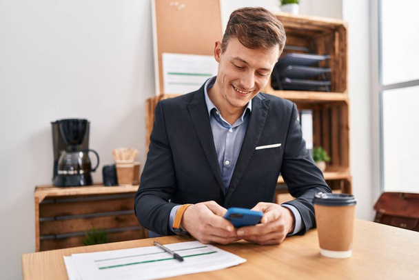 Молодой человек бизнес-работник, используя смартфон, работающий в офисе - Фото, изображение
