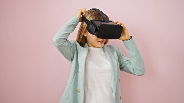 jong blond vrouw zakenman met behulp van virtual reality bril over geïsoleerde roze achtergrond - Foto, afbeelding
