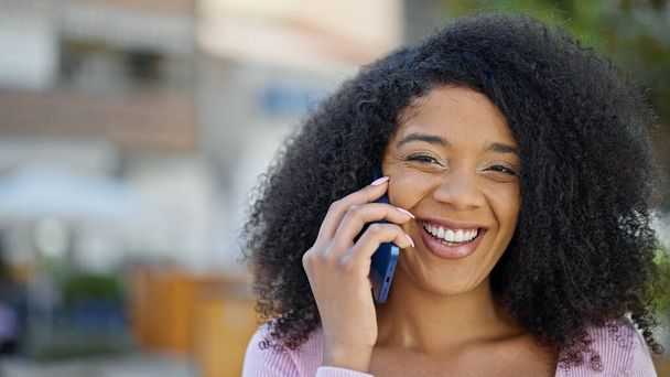 Afro-Amerikaanse vrouw glimlachen zelfverzekerd praten op de smartphone in het park - Foto, afbeelding