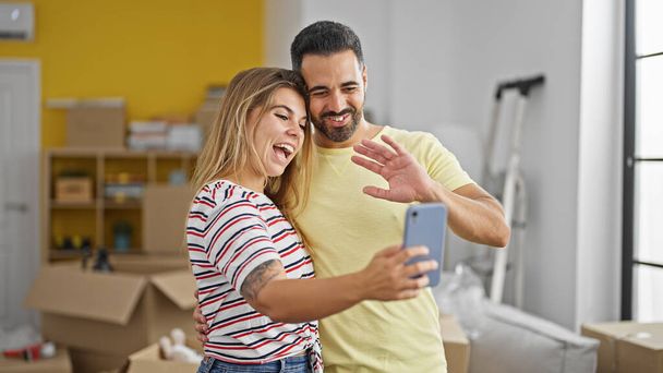 Чоловік і жінка пара обіймають один одного, маючи відеодзвінок в новому будинку - Фото, зображення