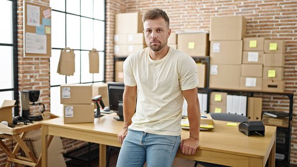 Młody człowiek e-commerce pracownik stojący z relaksującą ekspresją w biurze - Zdjęcie, obraz