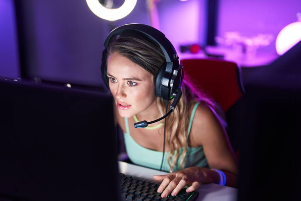 Молода блондинка стример грає в відеоігри за допомогою комп'ютера в ігровій кімнаті
 - Фото, зображення