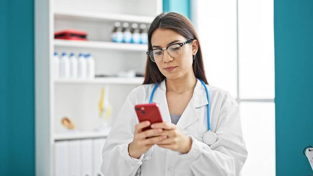 Jeune belle hispanique femme médecin en utilisant smartphone à la clinique - Photo, image