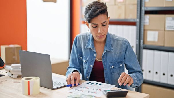Fiatal gyönyörű spanyol nő e-kereskedelem üzleti dolgozó segítségével számológép az irodában - Fotó, kép