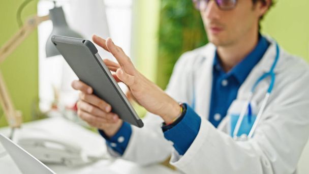 Joven médico hispano usando touchpad trabajando en la clínica - Foto, imagen