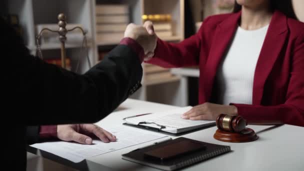Legal consultant makes agreements with clients by shaking hands and signing contracts and agreements. Female lawyer signing contract with client and shaking hands in office - Footage, Video