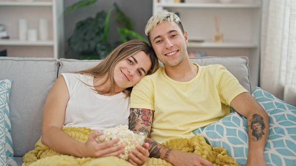 自宅で笑顔でポップコーンを食べる美しいカップル - 写真・画像