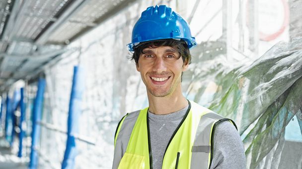 Jonge Spaanse man architect glimlacht vol vertrouwen staand op de bouwplaats - Foto, afbeelding
