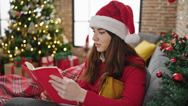 Fiatal spanyol nő olvas könyvet ünneplő karácsony otthon - Fotó, kép