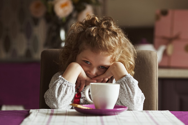 Little  beautiful girl sitting at the kitchen table - Foto, Imagen