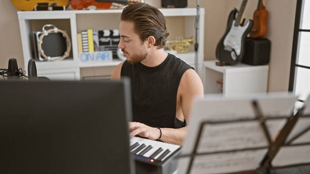 Fiatal spanyol férfi zenész zongorázik a zenei stúdióban - Fotó, kép