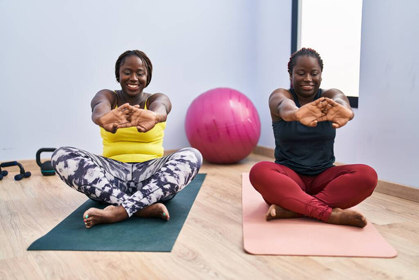 African american women smiling confident stretching arms at sport center - Photo, Image