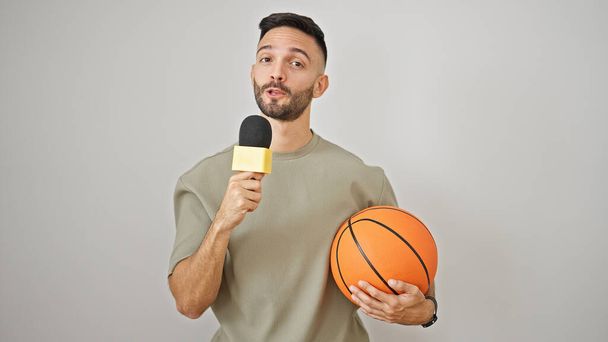 Fiatal spanyol férfi kosárlabda riporter dolgozik mikrofonnal izolált fehér háttér - Fotó, kép