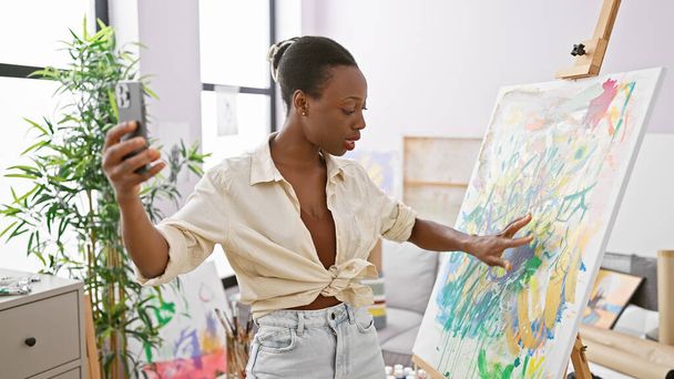 Впевнена афроамериканська жінка-художниця з радістю демонструє свій красивий художній малюнок на відеодзвінок від її надихаючої студії - Фото, зображення