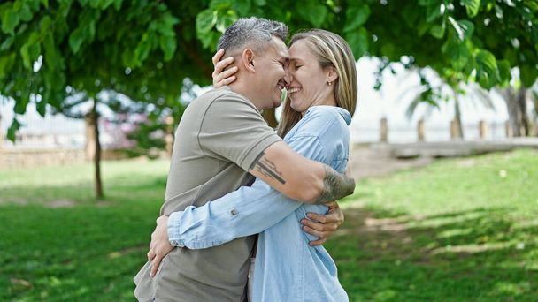 mężczyzna i kobieta para przytulają się uśmiechając się w parku - Zdjęcie, obraz