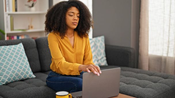 Mujer afroamericana usando laptop bebiendo café en casa - Foto, imagen