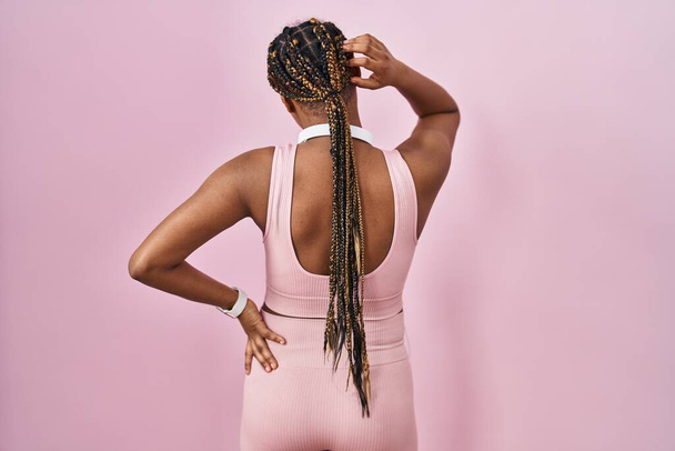 African american woman with braids wearing sportswear and headphones backwards thinking about doubt with hand on head  - Foto, Imagem