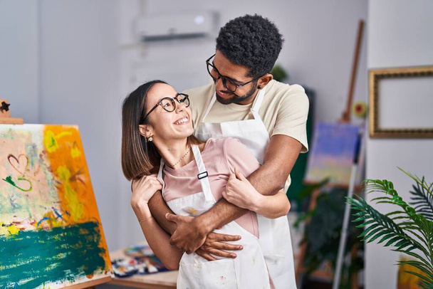 Mężczyzna i kobieta artyści uśmiechający się pewnie przytulając się w studio sztuki - Zdjęcie, obraz