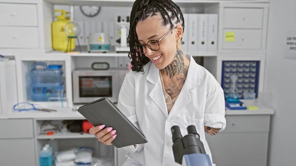 Sorrindo mulher amputada hispânica, dominando confiantemente seu touchpad no laboratório de alta tecnologia - Foto, Imagem