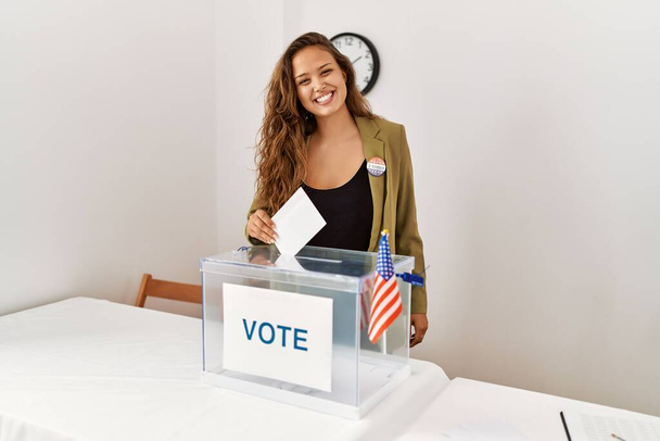 Young beautiful hispanic woman electoral table president putting vote in box at electoral college - Photo, Image