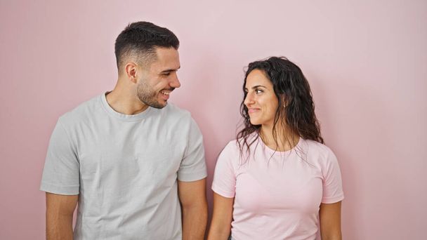 Mann und Frau stehen zusammen und schauen einander über isolierten rosa Hintergrund an - Foto, Bild