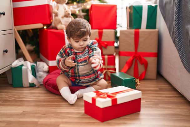 Adorable hispanic toddler sitting on floor by christmas gifts at home - Photo, Image