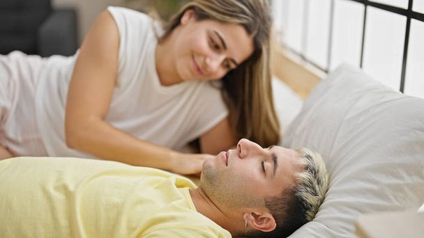 Kaunis pari makaa sängyllä etsivät poikaystävä nukkuessaan makuuhuoneessa - Valokuva, kuva