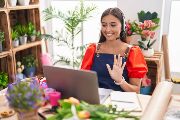Young hispanic woman working at florist shop doing video call looking positive and happy standing and smiling with a confident smile showing teeth  - Photo, Image