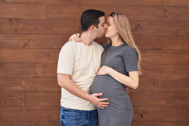 Mies ja nainen pari odottaa vauva suudella yli eristetty puinen tausta - Valokuva, kuva