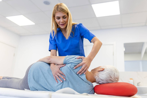 Medico o fisioterapista aiuta a guarire la schiena di una donna anziana. e dare consigli all'interno del centro di riabilitazione. Concetto di riabilitazione fisica. - Foto, immagini