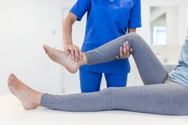 Physiotherapist working with patient in clinic, closeup. A Modern rehabilitation physiotherapy worker with senior client, Physical therapist stretching patient knee - Photo, Image