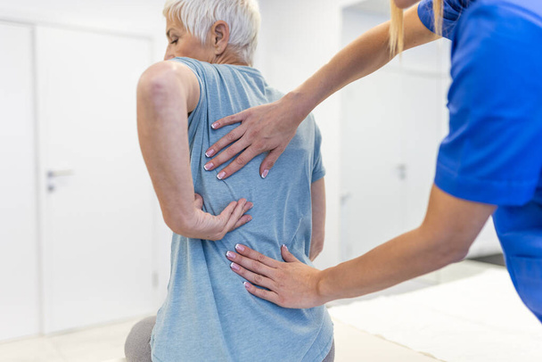 Kıdemli kadın kiropraktik sırt düzeltmesi yaptırıyor. Osteopati, alternatif tıp, ağrı kesici konsepti. Fizyoterapi, yaralanma rehabilitasyonu - Fotoğraf, Görsel