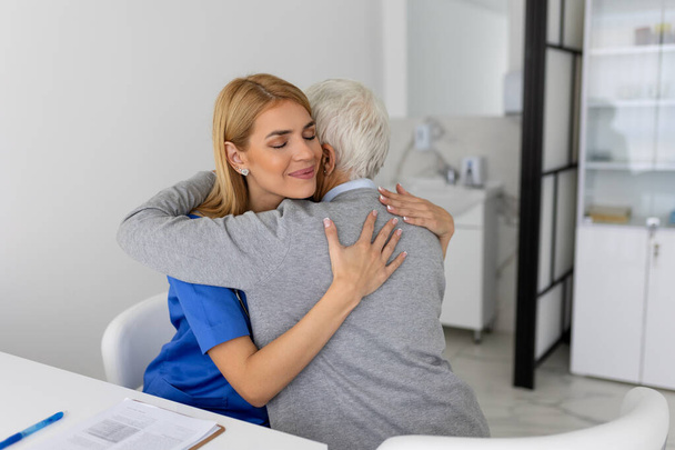 The elderly woman enjoys an embrace from her favorite healthcare doctor. Medical care, young female doctor hugging patient. Empathy concept. Elderly woman hugging caregiver - Photo, Image