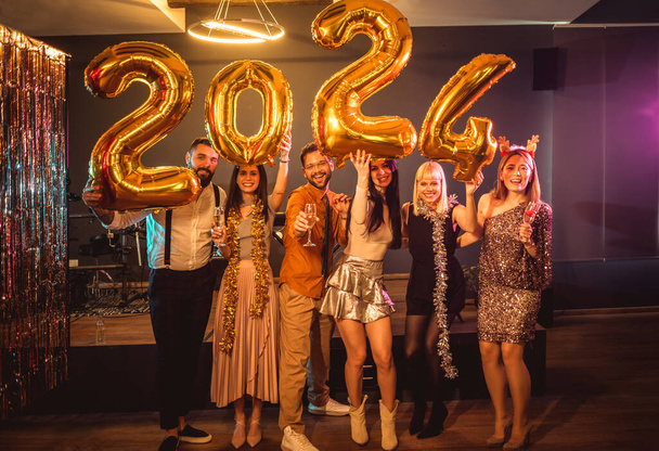 Gruppo di giovani che festeggiano il nuovo anno al nightclub. Hanno dei palloncini con il numero d'oro. - Foto, immagini
