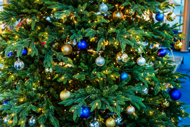 Árbol de Navidad decorado con bolas y guirnaldas azules y doradas - Foto, Imagen