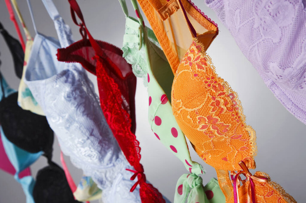Um grupo de sutiãs coloridos pendurar em uma linha de roupas em um ambiente de estúdio - Foto, Imagem