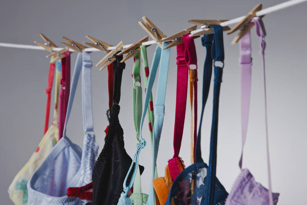 Μια ομάδα πολύχρωμων σουτιέν κρέμονται σε μια γραμμή ρούχων σε ένα περιβάλλον στούντιο - Φωτογραφία, εικόνα