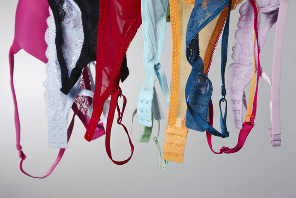 A group of colorful bras hang on a clothes line in a studio environment - Photo, Image