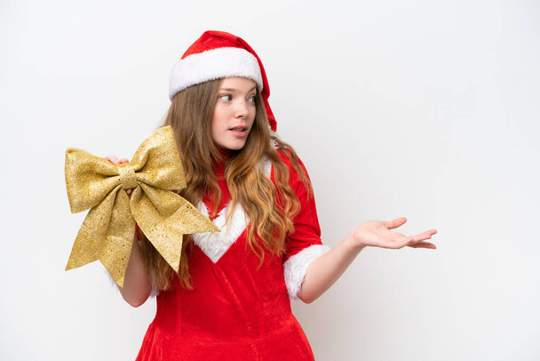 Young caucasian woman with Christmas dress holding Christmas bow isolated on white background with surprise facial expression - Photo, Image