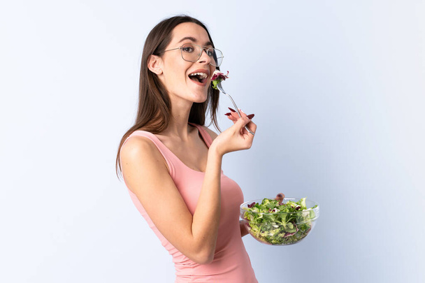 junge Frau mit Salat über isolierte Mauer - Foto, Bild