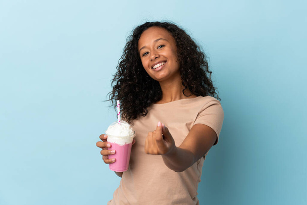 Adolescente avec milkshake fraise isolé sur fond bleu faisant geste d'argent - Photo, image