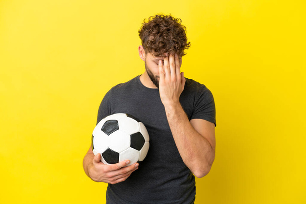 Όμορφος νεαρός ποδοσφαιριστής άνδρας απομονωμένος σε κίτρινο φόντο με κουρασμένη και άρρωστη έκφραση - Φωτογραφία, εικόνα