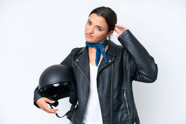 Young caucasian woman with a motorcycle helmet isolated on blue background having doubts - Photo, Image