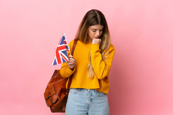 Fiatal szőke nő kezében egy Egyesült Királyság zászló elszigetelt fehér háttér kételyek - Fotó, kép