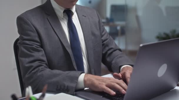 Porträt eines nachdenklichen Geschäftsmannes, der im modernen Büro an einem drahtlosen Laptop arbeitet und dabei in die Kamera blickt - Filmmaterial, Video