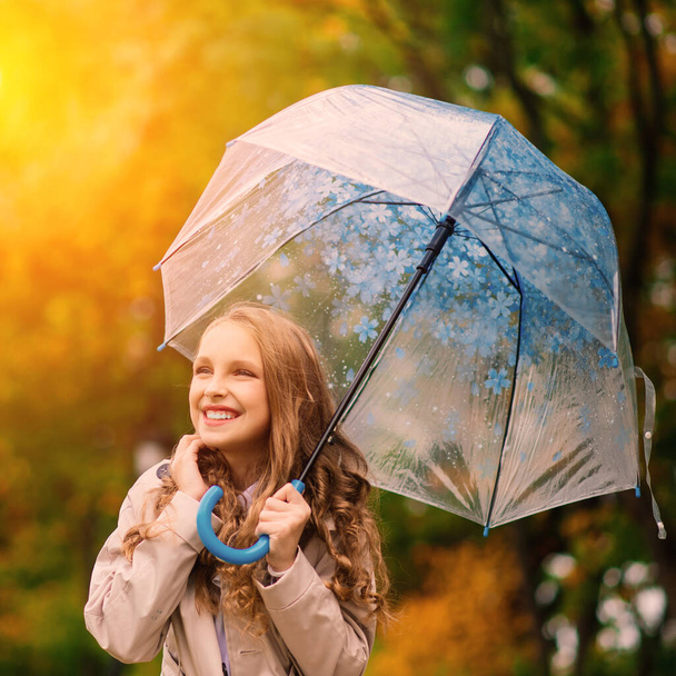 Νεαρό ελκυστικό χαμογελαστό κορίτσι κάτω από ομπρέλα σε ένα φθινόπωρο δάσος - Φωτογραφία, εικόνα
