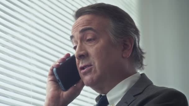 Close up zralého podnikatele pomocí mobilního telefonu volat svého obchodního partnera diskutovat podrobnosti o nové dohodě na úřadu - Záběry, video