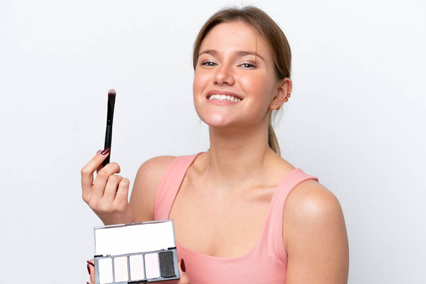 Mladá běloška žena izolované na bílém pozadí s make-up paleta a šťastný - Fotografie, Obrázek