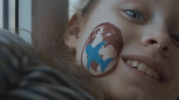 Pintura de transporte aéreo internacional no rosto de uma menina alegre. Conceito de carga e transporte - Filmagem, Vídeo